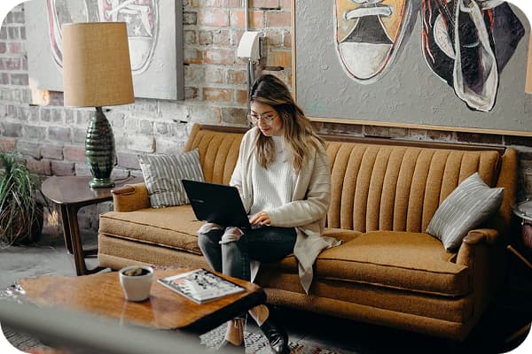 Woman sitting on a couch working on laptop